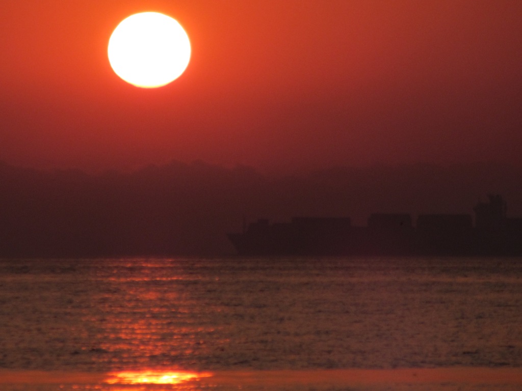 черное море на восходе, контейнеровоз на рейде в лучах заката.